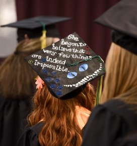 A cap at graduation reads "She began to believe that very few things are indeed impossible"
