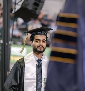 A graduate walks toward stage to receive his diploma