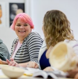 A student smiles as she and her classmates discuss an anthropology lab