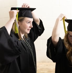 A graduate adjusts her tassel before walking into Commencement 2023