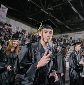 A SUNY Adirondack graduate flips a peace sign at Commencement 2024