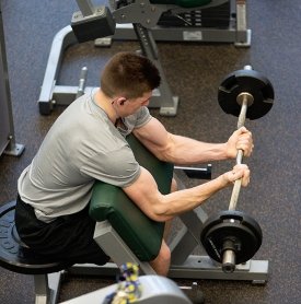 A student does bicep curls in the Residence Hall Fitness Center