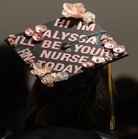 A graduation cap is seen from above and reads, "Hello, my name is Alyssa and I'll be your nurse today."