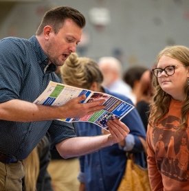 An employer reviews a pamphlet with a student at a 2024 job fair