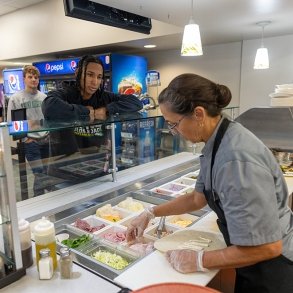 Students wait in line at the deli counter of the college's dining hall