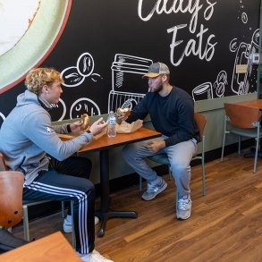 Two students visit over coffees at Eddy's Eats, the on-campus cafe