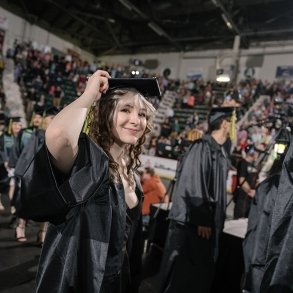 A graduate beams proudly as she walks into commencement 2024