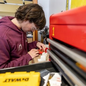 A student leans over equipment during an Advanced Manufacturing course