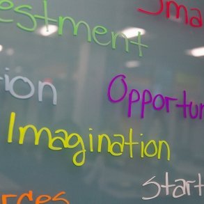 Closeup image of a marker board with inspiring words about business including "entrepreneurship," "imagination," etc.