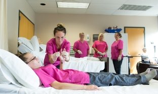 Students learn health care techniques in a training session