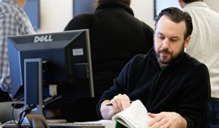 A man does classwork at a desk