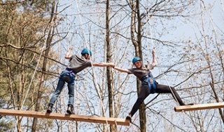 Two students participate in a ropes activity on the SUNY Adirondack Adventure Course