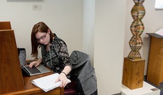 A student uses a computer at a desk in the library