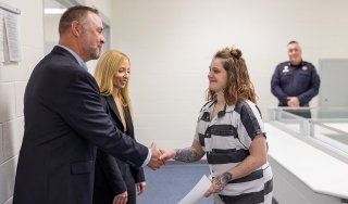 Dean for Extended Programs Mike Prutsman and Chief Human Resources Officer Mindy Wilson present a Business of Life completion certificate to a participate in the program at Warren County Jail.