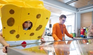Someone dressed as SpongeBob SquarePants plays an arcade-style video game
