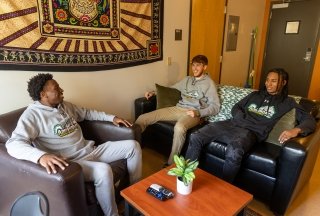 Three male students talking in a dorm room