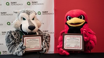 SUNY Adirondack mascot Eddy Rondack celebrates with SUNY Plattsburgh mascot Burghy after the colleges' presidents signed a dual acceptance agreement