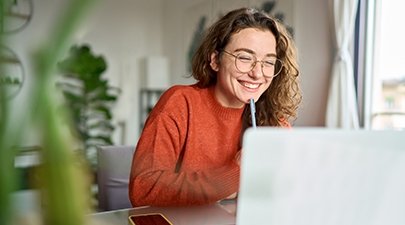 Stock image of a young woman smiling while in an on-screen meeting