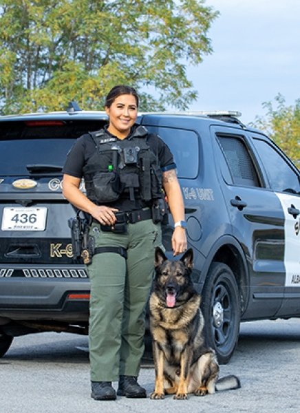 Albany County Sheriff's Officer Kayla Apple stands beside a police car, with a canine officer
