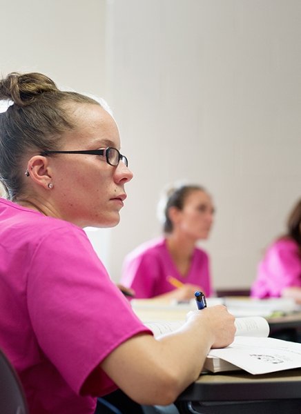Image of students in pink health care scrubs learning about being personal care aides