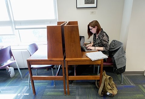 A student works on a laptop in a study space in the SUNY Adirondack library