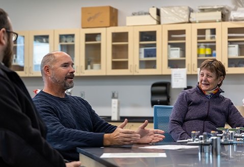 Faculty members converse at a lab station