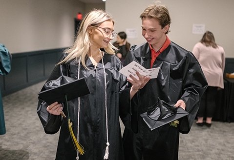 Two graduates look over materials before the ceremony.