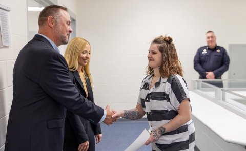 Dean for Extended Programs Mike Prutsman and Chief Human Resources Officer Mindy Wilson present a Business of Life completion certificate to a participate in the program at Warren County Jail.