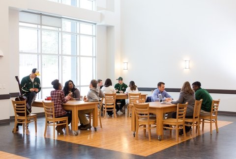 Students sit at tables in the Multipurpose Room of the Residence Hall