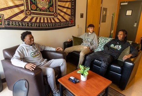 Three students sit on couches in the Residence Hall