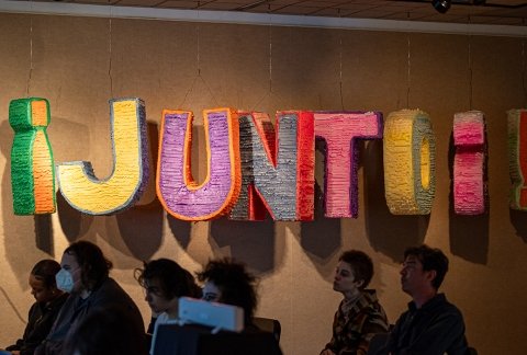 The word JUNTO spelled out in giant 3D, paper letters