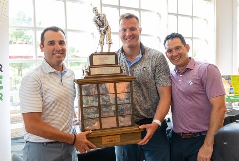 Three golfers pose with a trophy at the Lyman A. Beeman Golf Tournament 