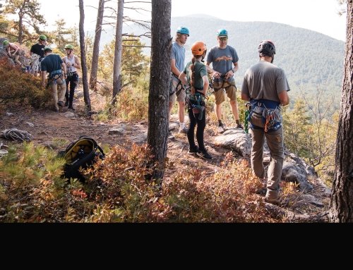 Students on top of a mountain in helmets preparing to rock climb