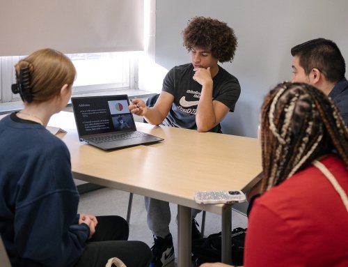 group of students working together with one presenting on a laptop