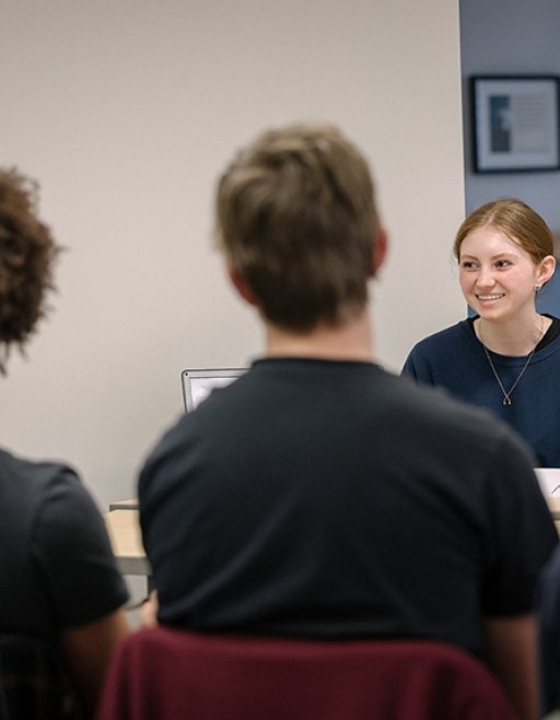 A student smiles as she presents in an English course